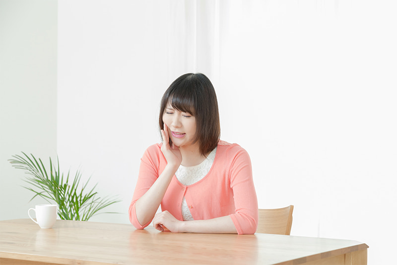 痛そうに口元を抑える女性