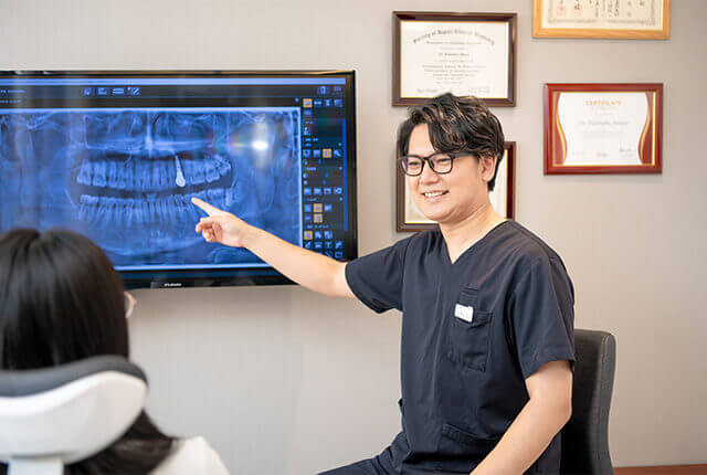 患者に歯の治療の流れについて説明を行う歯科医師