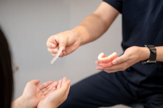 入れ歯の模型を持つ歯科医師と患者
