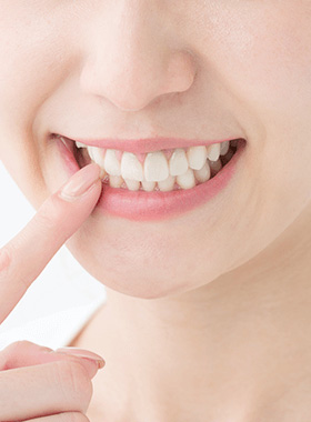 口元を指さす女性