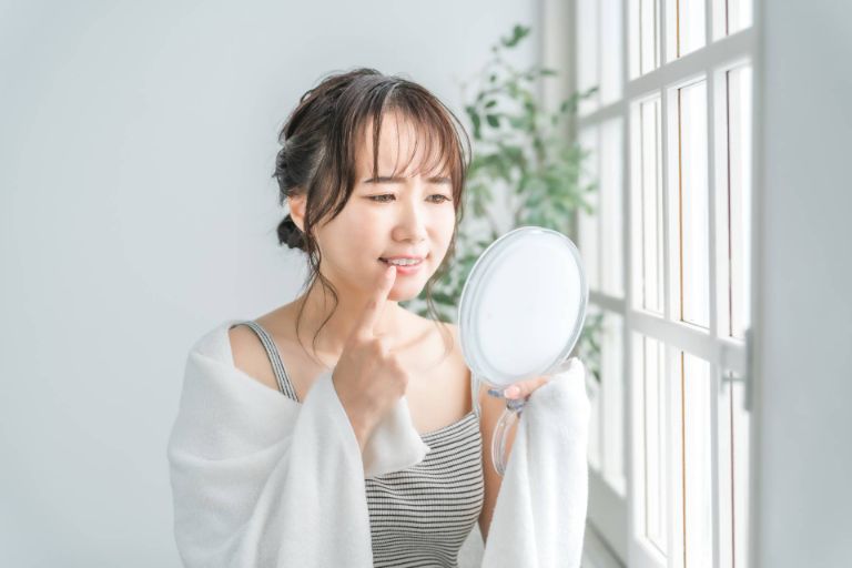 手鏡で欠けた歯を見ている女性