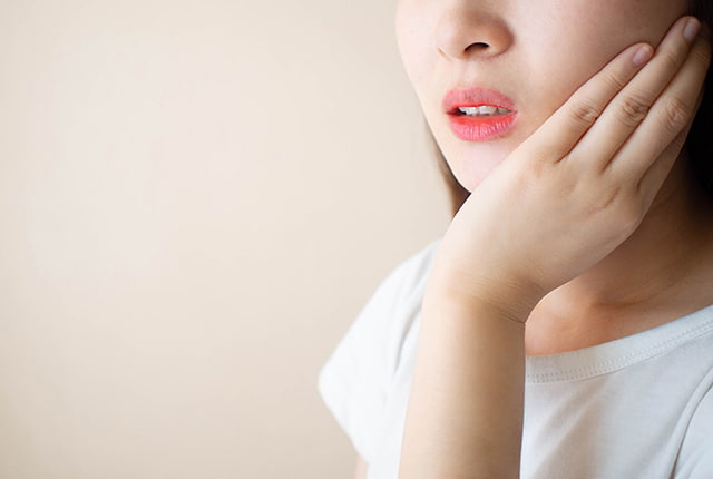 痛そうに口元を抑える女性