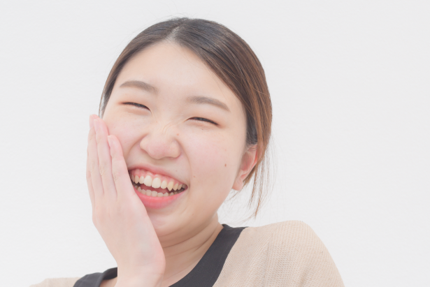 女性歯科衛生士スタッフが頬に手を当て笑っている様子