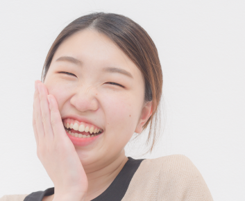女性歯科衛生士スタッフが頬に手を当て笑っている様子